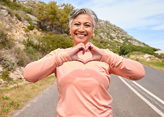 Image showing Senior woman, heart hands and runner on road for fitness, love icon and portrait for smile, workout or health. Mature lady, sign language and emoji with wellness, exercise and retirement in mountains