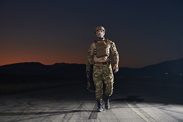 Image showing A professional soldier in full military gear striding through the dark night as he embarks on a perilous military mission