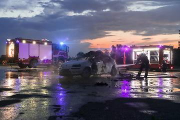 Image showing Firefighters using water fire extinguisher to fighting with the fire flame in car accident. Firefighter industrial and public safety concept rescue in night.