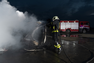 Image showing Firefighters using water fire extinguisher to fighting with the fire flame in car accident. Firefighter industrial and public safety concept rescue in night.