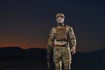 Image showing A professional soldier in full military gear striding through the dark night as he embarks on a perilous military mission