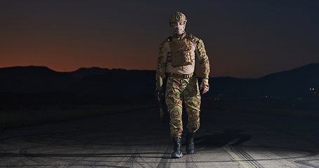 Image showing A professional soldier in full military gear striding through the dark night as he embarks on a perilous military mission