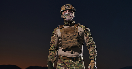 Image showing A professional soldier in full military gear striding through the dark night as he embarks on a perilous military mission