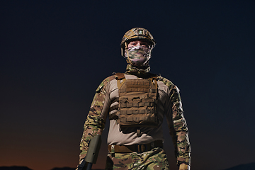 Image showing A professional soldier in full military gear striding through the dark night as he embarks on a perilous military mission