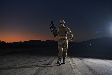 Image showing A professional soldier in full military gear striding through the dark night as he embarks on a perilous military mission