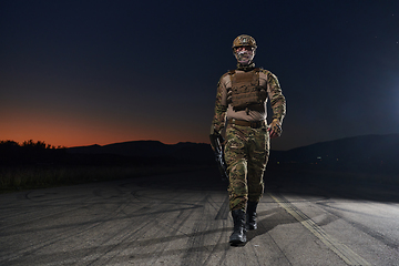 Image showing A professional soldier in full military gear striding through the dark night as he embarks on a perilous military mission