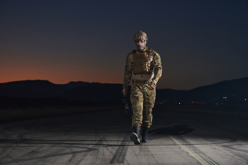 Image showing A professional soldier in full military gear striding through the dark night as he embarks on a perilous military mission