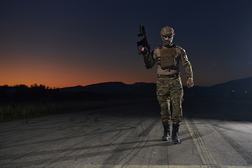 Image showing A professional soldier in full military gear striding through the dark night as he embarks on a perilous military mission