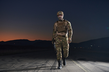 Image showing A professional soldier in full military gear striding through the dark night as he embarks on a perilous military mission