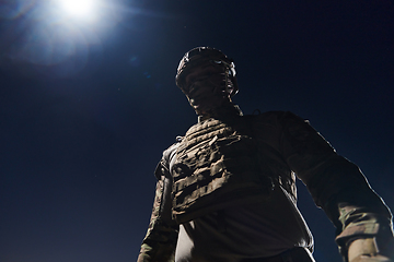 Image showing A professional soldier in full military gear striding through the dark night as he embarks on a perilous military mission