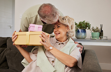 Image showing Gift, surprise and a senior couple on their anniversary for celebration in their home living room together. Love, present and birthday with a husband giving his wife a box while sitting on a sofa