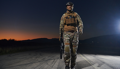 Image showing A professional soldier in full military gear striding through the dark night as he embarks on a perilous military mission