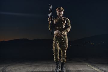 Image showing A professional soldier in full military gear striding through the dark night as he embarks on a perilous military mission