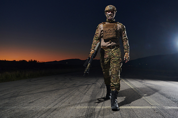Image showing A professional soldier in full military gear striding through the dark night as he embarks on a perilous military mission
