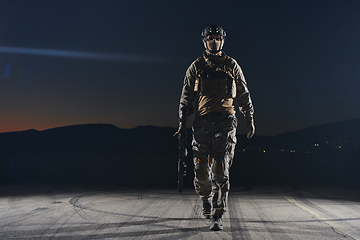 Image showing A professional soldier in full military gear striding through the dark night as he embarks on a perilous military mission