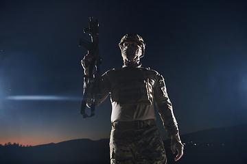 Image showing A professional soldier in full military gear striding through the dark night as he embarks on a perilous military mission