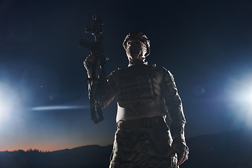 Image showing A professional soldier in full military gear striding through the dark night as he embarks on a perilous military mission