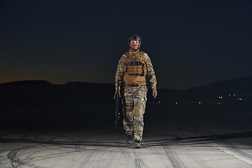 Image showing A professional soldier in full military gear striding through the dark night as he embarks on a perilous military mission