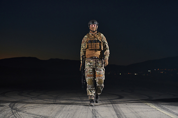 Image showing A professional soldier in full military gear striding through the dark night as he embarks on a perilous military mission