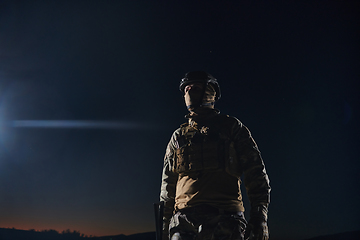 Image showing A professional soldier in full military gear striding through the dark night as he embarks on a perilous military mission