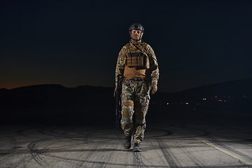 Image showing A professional soldier in full military gear striding through the dark night as he embarks on a perilous military mission