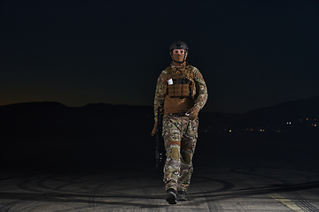 Image showing A professional soldier in full military gear striding through the dark night as he embarks on a perilous military mission