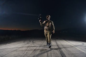 Image showing A professional soldier in full military gear striding through the dark night as he embarks on a perilous military mission