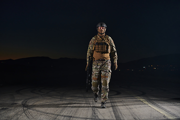 Image showing A professional soldier in full military gear striding through the dark night as he embarks on a perilous military mission