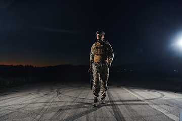 Image showing A professional soldier in full military gear striding through the dark night as he embarks on a perilous military mission