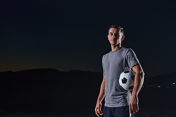 Image showing Portrait of a young handsome soccer player man on a street playing with a football ball.
