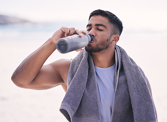 Image showing Fitness, sports and man drinking water at the beach after running, training or morning cardio workout with bottle. Exercise, break and thirsty Indian male runner or person with hydration drink at sea