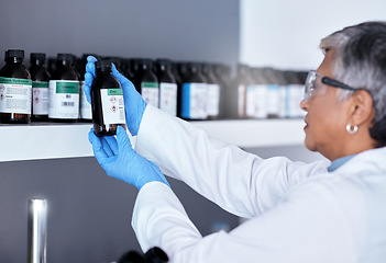 Image showing Laboratory, science and woman with bottle from shelf to check medical research information. Healthcare, medicine and innovation in manufacturing of vaccine or prescription drugs with senior scientist