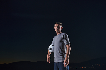 Image showing Portrait of a young handsome soccer player man on a street playing with a football ball.