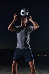 Image showing Portrait of a young handsome soccer player man on a street playing with a football ball