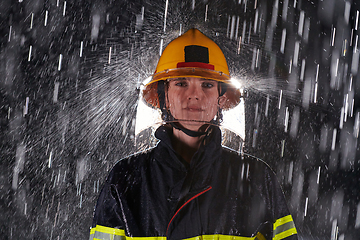 Image showing A determined female firefighter in a professional uniform striding through the dangerous, rainy night on a daring rescue mission, showcasing her unwavering bravery and commitment to saving lives.