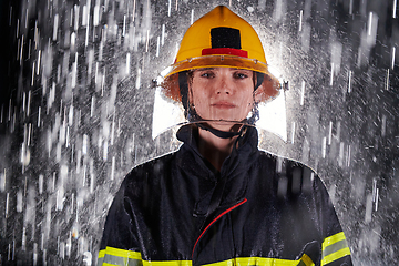 Image showing A determined female firefighter in a professional uniform striding through the dangerous, rainy night on a daring rescue mission, showcasing her unwavering bravery and commitment to saving lives.