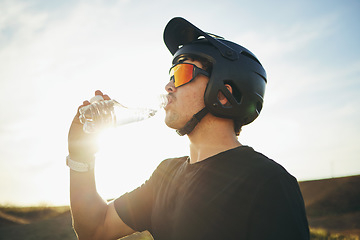 Image showing Biker, drinking water and man with helmet and sunglasses outdoor in nature for sports training workout. Sky, thirst or wellness of male person with hydration for off road cycling, travel or adventure