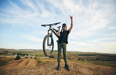 Image showing Hand sign, mountain bike and man outdoor in nature for extreme sports, training or workout. Rock on, cool attitude and male person with bicycle for off road cycling, countryside travel or adventure