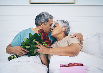 Image showing Love, elderly couple and kiss with roses in bed, romance and affection in home. Flowers, senior man and woman in bedroom for intimacy, care and enjoying quality time together with floral bouquet gift