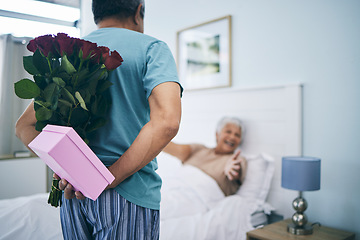 Image showing Gift, surprise and a senior couple on their anniversary in the bedroom of their house together for celebration in the morning. Flowers, birthday box and an old man giving his wife a present at home