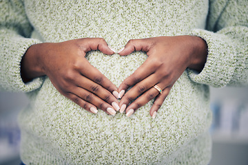 Image showing Pregnancy, closeup and woman with a heart shape on her maternal belly for care and motherhood. Health, zoom and African pregnant female person hands on stomach with a love sign or emoji for her baby.
