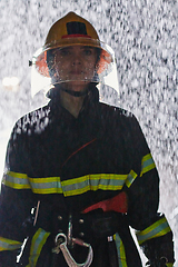 Image showing A determined female firefighter in a professional uniform striding through the dangerous, rainy night on a daring rescue mission, showcasing her unwavering bravery and commitment to saving lives.