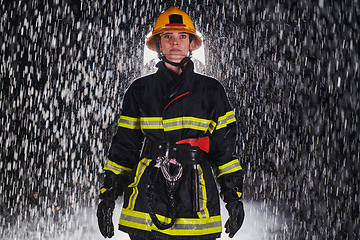 Image showing A determined female firefighter in a professional uniform striding through the dangerous, rainy night on a daring rescue mission, showcasing her unwavering bravery and commitment to saving lives.