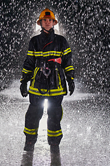 Image showing A determined female firefighter in a professional uniform striding through the dangerous, rainy night on a daring rescue mission, showcasing her unwavering bravery and commitment to saving lives.