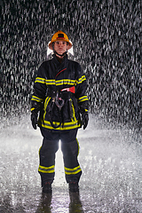 Image showing A determined female firefighter in a professional uniform striding through the dangerous, rainy night on a daring rescue mission, showcasing her unwavering bravery and commitment to saving lives.