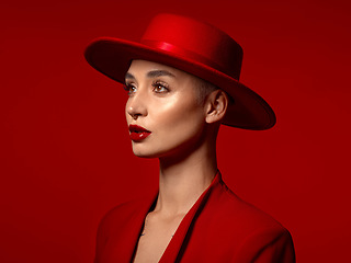 Image showing Vision, fashion and a model woman on a red studio background for elegant or trendy style. Aesthetic, art and hat with a young female person looking edgy or classy in a suit or unique clothes