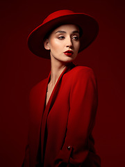 Image showing Idea, fashion and woman in red hat in studio isolated on a background with suit. Makeup, cosmetics and female model in fedora, serious style and classy clothes with aesthetic, vision and thinking.