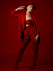 Image showing Runway model, fashion and a woman on a red studio background for elegant or trendy style. Aesthetic, art and luxury beauty with a young female person looking edgy or classy in a suit on a catwalk