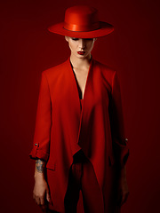 Image showing Fashion, suit and hat on woman with beauty in studio with retro, style and edgy, confident or creative pose on red background mockup. Mystery character, model and girl with power or vintage aesthetic