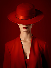 Image showing Beauty, fashion and woman in a vintage suit with hat in studio with retro, style and edgy, confident or creative pose on red background. Mystery character, model and girl with power or aesthetic